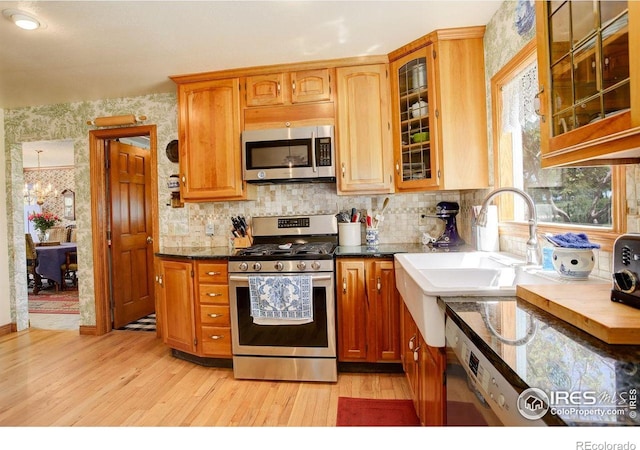 2219 Meadow Green Cir, Franktown, CO 80116 - kitchen featuring appliances with stainless steel finishes, light wood finished floors, backsplash, glass insert cabinets, and wallpapered walls