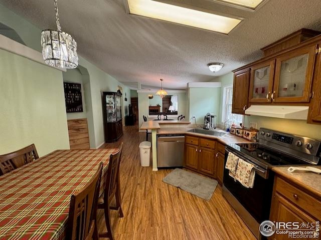 kitchen featuring stainless steel appliances, exhaust hood, light wood-style floors, a peninsula, and a textured ceiling