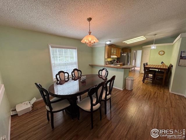 dining space featuring dark wood finished floors, a chandelier, a textured ceiling, and baseboards