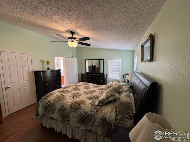 bedroom featuring dark wood-style floors, a textured ceiling, ceiling fan, and a textured wall