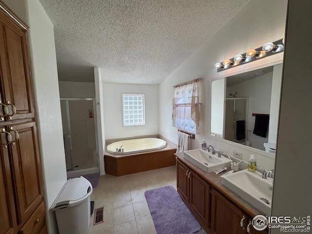 bathroom with a textured ceiling, a stall shower, a bath, double vanity, and tile patterned floors