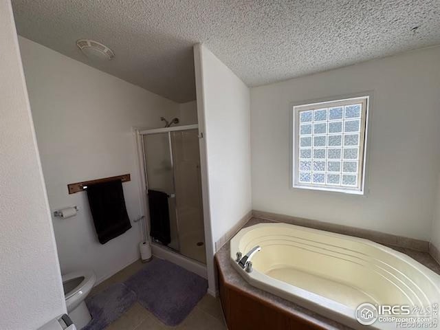 bathroom featuring a textured ceiling, a stall shower, a bath, toilet, and tile patterned floors