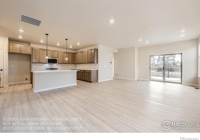 kitchen with stainless steel microwave, recessed lighting, light countertops, backsplash, and light wood-type flooring