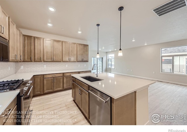 kitchen with a sink, stainless steel appliances, light wood-style floors, decorative backsplash, and recessed lighting