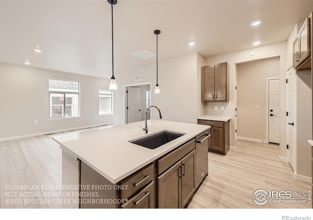 kitchen with a sink, light wood-style floors, stainless steel dishwasher, light countertops, and recessed lighting