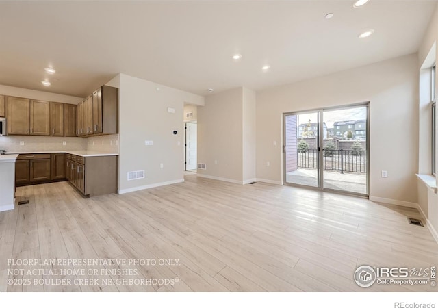 kitchen featuring light wood-style flooring, recessed lighting, light countertops, tasteful backsplash, and baseboards