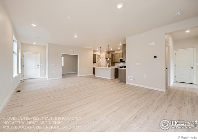 unfurnished living room featuring light wood-style floors, baseboards, and recessed lighting