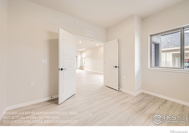 spare room featuring light wood finished floors and baseboards