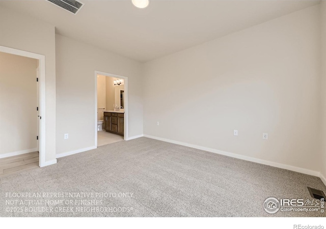 unfurnished bedroom with light carpet, baseboards, and ensuite bathroom