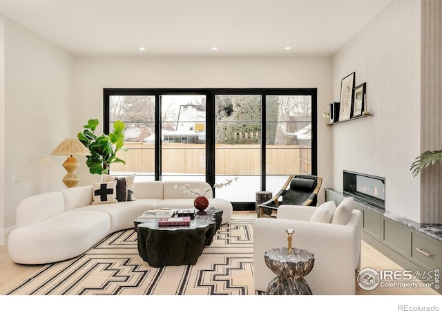 living area with a glass covered fireplace, recessed lighting, and wood finished floors