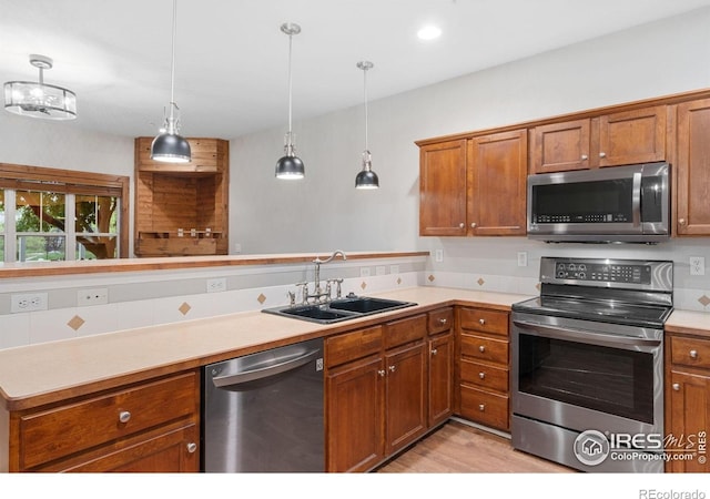 kitchen featuring stainless steel appliances, a sink, brown cabinetry, and light countertops