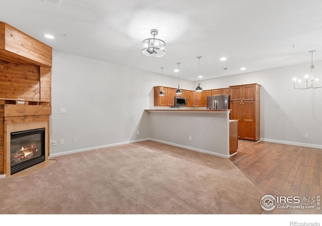 unfurnished living room with a chandelier, recessed lighting, baseboards, a large fireplace, and light colored carpet