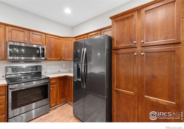 kitchen with stainless steel appliances, brown cabinets, light wood-type flooring, and recessed lighting