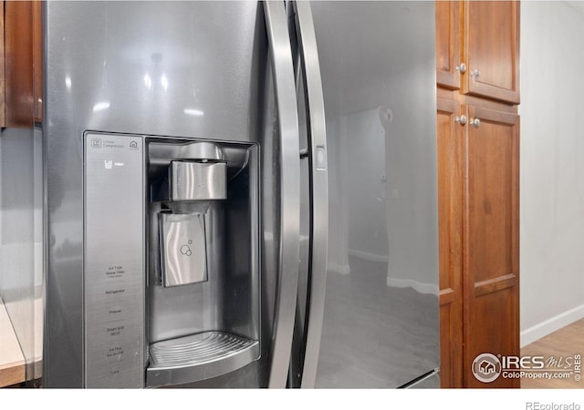 kitchen with stainless steel fridge, baseboards, and brown cabinetry
