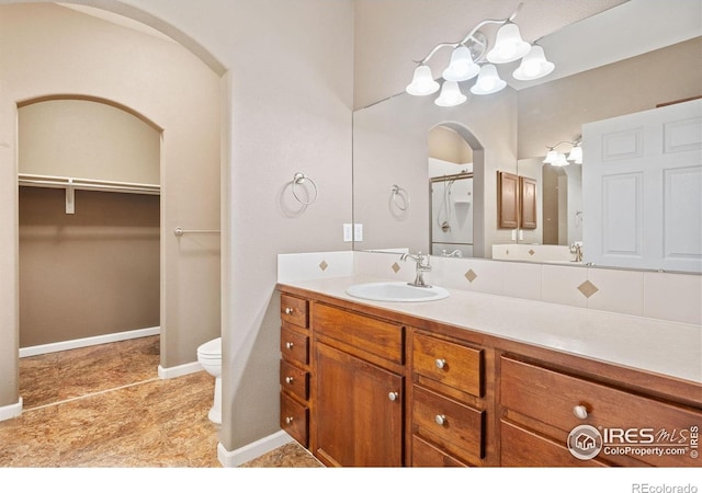 full bathroom featuring toilet, vanity, baseboards, and a spacious closet