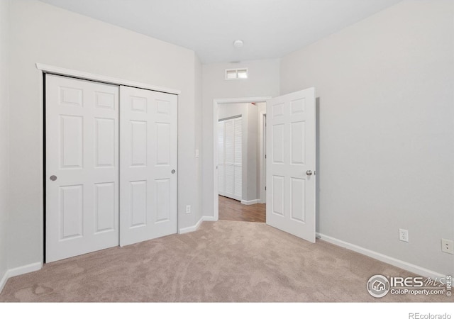 unfurnished bedroom with carpet floors, a closet, and baseboards