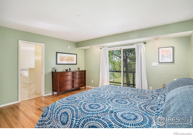 bedroom with wood finished floors, access to outside, baseboards, and ensuite bath