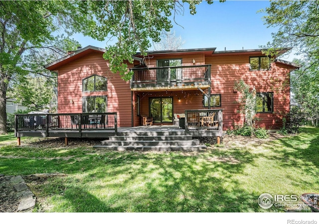 rear view of property featuring a balcony, a yard, and a deck