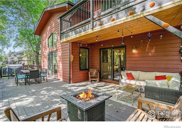 wooden deck with an outdoor living space with a fire pit, outdoor dining space, and area for grilling