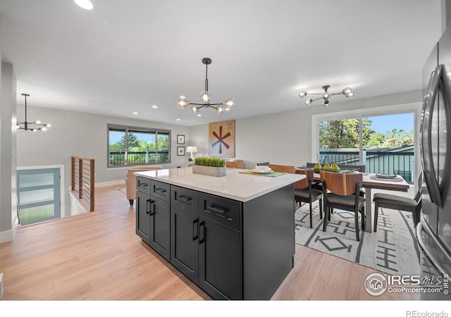 kitchen with a chandelier, freestanding refrigerator, dark cabinets, light wood-style floors, and recessed lighting