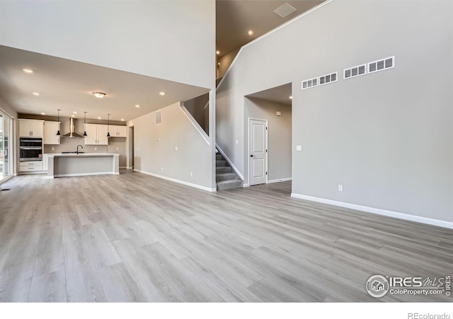 2710 Crystal Spgs, Longmont, CO 80503 - unfurnished living room featuring stairs, light wood-type flooring, recessed lighting, and a towering ceiling