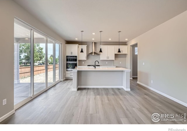 2710 Crystal Spgs, Longmont, CO 80503 - kitchen featuring wall chimney range hood, recessed lighting, light countertops, plenty of natural light, and light wood-type flooring