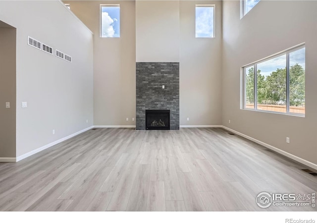 2710 Crystal Spgs, Longmont, CO 80503 - unfurnished living room with a high ceiling, light wood-type flooring, healthy amount of natural light, and a fireplace
