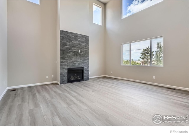 2710 Crystal Spgs, Longmont, CO 80503 - unfurnished living room featuring a towering ceiling, wood finished floors, and a glass covered fireplace