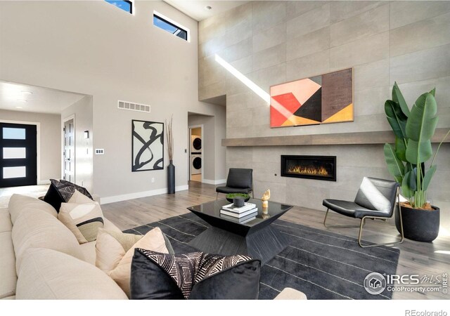 2123 Picture Point Dr, Windsor, CO 80550 - living area featuring wood finished floors, estacked washer and dryer, a towering ceiling, baseboards, and a fireplace