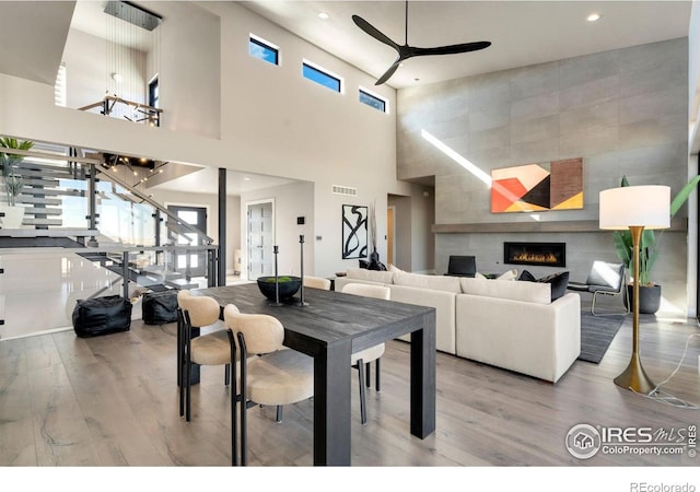 2123 Picture Point Dr, Windsor, CO 80550 - dining room with ceiling fan, wood finished floors, a towering ceiling, a tiled fireplace, and recessed lighting