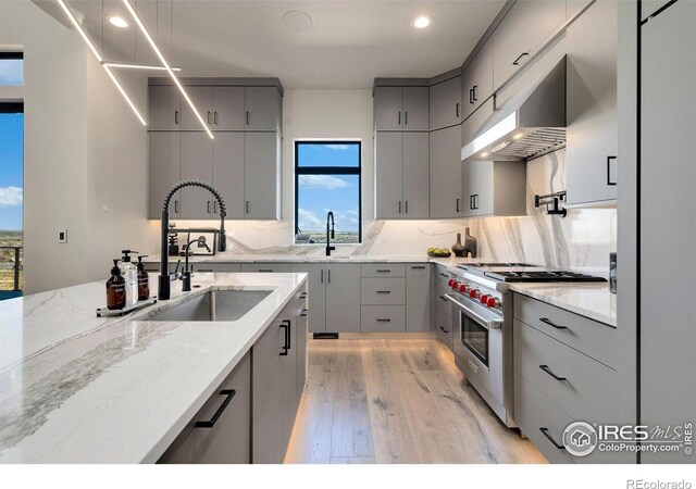 2123 Picture Point Dr, Windsor, CO 80550 - kitchen with gray cabinets, stainless steel stove, a sink, light wood-style floors, and under cabinet range hood