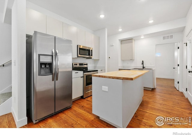 7864 5th St, Wellington, CO 80549 - kitchen with appliances with stainless steel finishes, wooden counters, light wood-style floors, a kitchen island, and recessed lighting