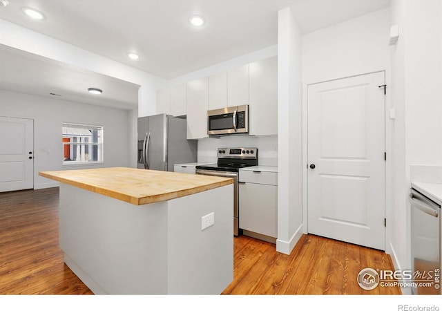 7864 5th St, Wellington, CO 80549 - kitchen with stainless steel appliances, light wood finished floors, wooden counters, recessed lighting, and white cabinetry