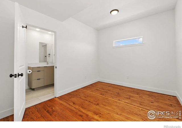 7864 5th St, Wellington, CO 80549 - unfurnished bedroom with light wood finished floors, baseboards, and ensuite bathroom