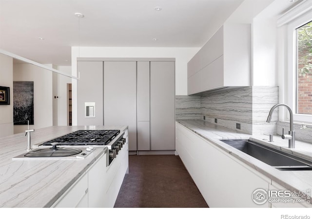 kitchen with a sink, white cabinetry, stainless steel gas stovetop, decorative backsplash, and modern cabinets