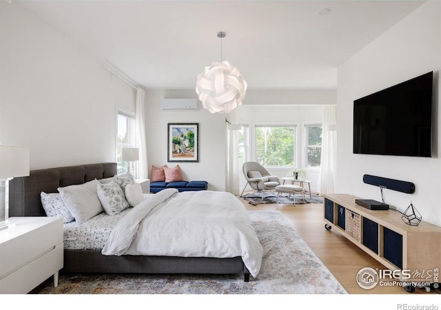 bedroom featuring a wall unit AC and wood finished floors