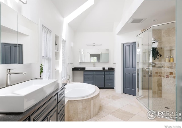full bathroom featuring a stall shower, a bath, tile patterned flooring, and two vanities