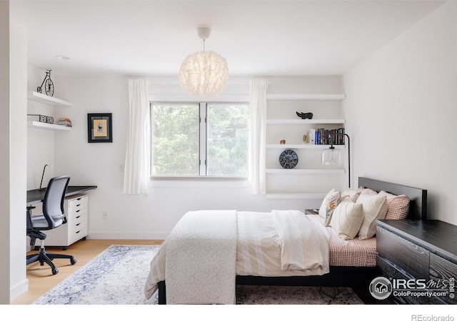 bedroom featuring an office area, wood finished floors, and baseboards