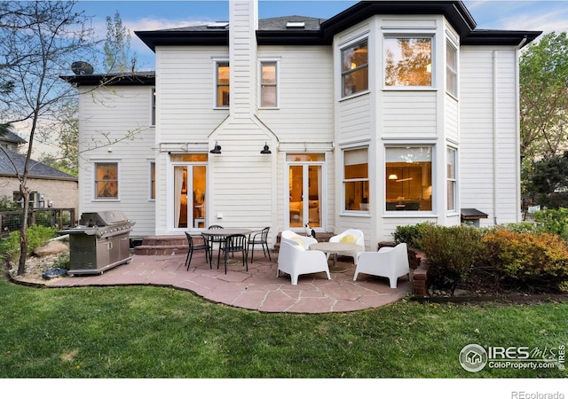 back of property featuring a patio area, a yard, and a chimney