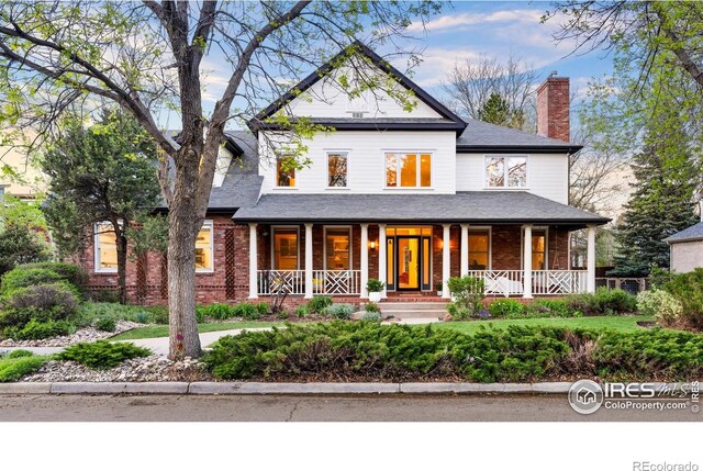 2835 Links Dr, Boulder, CO 80301 - view of front of house with covered porch, brick siding, a chimney, and roof with shingles