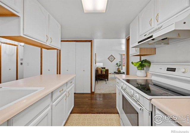 4560 Larkbunting Dr Unit 5D, Fort Collins, CO 80526 - kitchen featuring white range with electric stovetop, white cabinets, light countertops, under cabinet range hood, and dark wood finished floors