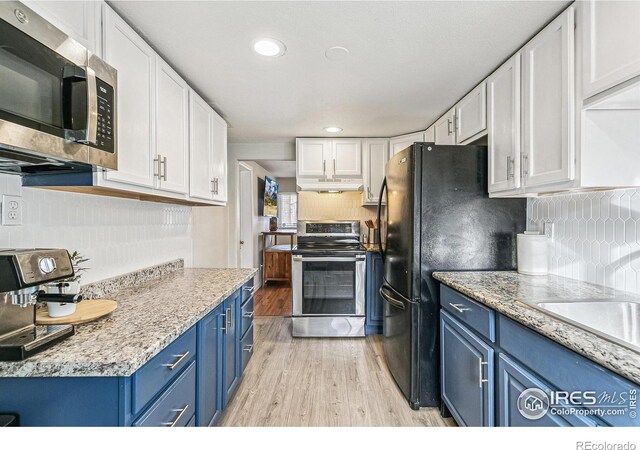 1970 Willow St, Denver, CO 80220 - kitchen with blue cabinets, appliances with stainless steel finishes, under cabinet range hood, white cabinetry, and light wood-type flooring