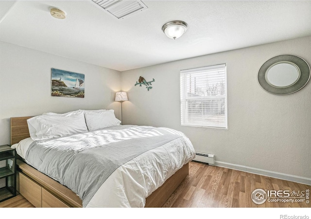 1970 Willow St, Denver, CO 80220 - bedroom featuring wood finished floors, baseboards, and a baseboard heating unit