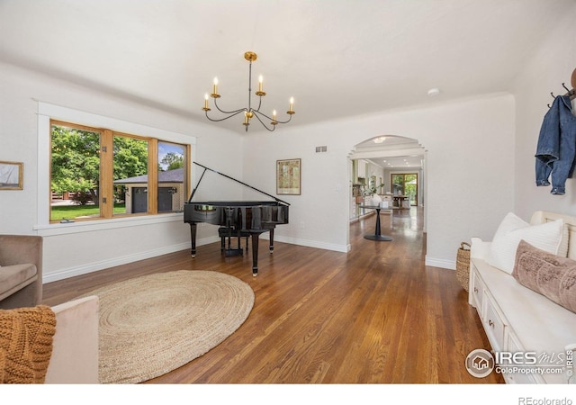 sitting room with arched walkways, wood finished floors, a chandelier, and baseboards