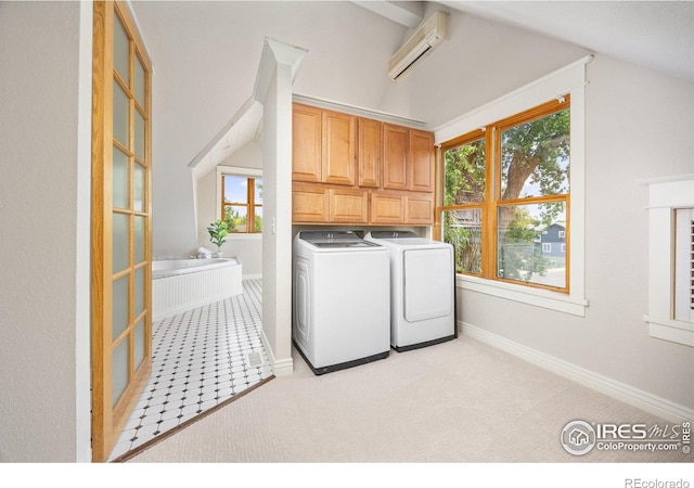 laundry area featuring washer and clothes dryer, a wall mounted air conditioner, cabinet space, and plenty of natural light
