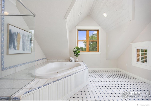 bathroom with vaulted ceiling, a bath, and baseboards