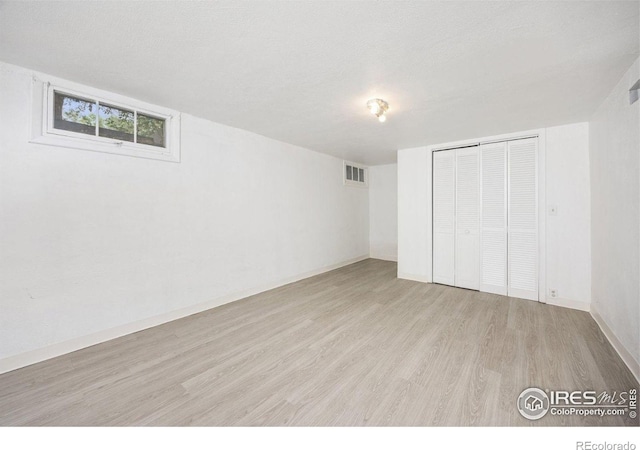 unfurnished bedroom featuring wood finished floors, a closet, and baseboards