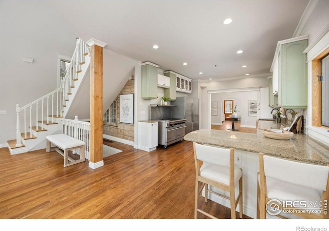 kitchen featuring green cabinets, recessed lighting, light wood-style flooring, a peninsula, and crown molding