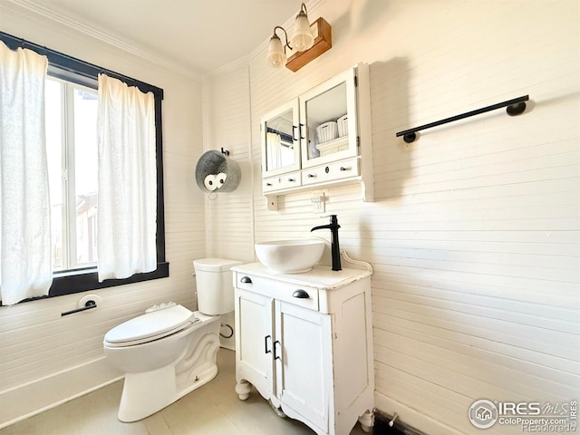 half bathroom with toilet, ornamental molding, and vanity
