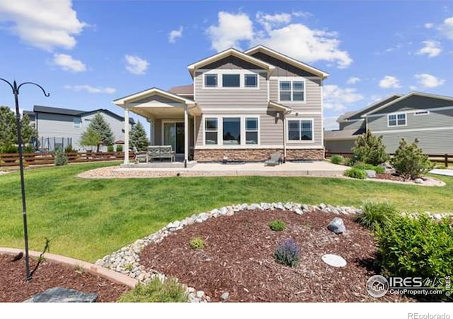 back of house with stone siding and a patio